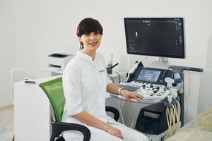 portrait d'un médecin obstétricien assis dans la salle de clinique avec appareil à ultrasons photo