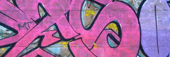 fragment de dessins de graffitis. le vieux mur décoré de taches de peinture dans le style de la culture de l'art de la rue. texture de fond colorée dans des tons violets photo