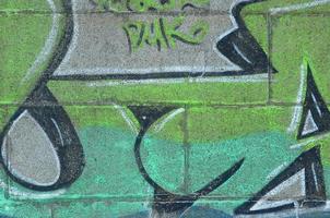fragment de dessins de graffitis. le vieux mur décoré de taches de peinture dans le style de la culture de l'art de la rue. texture de fond colorée dans des tons verts photo
