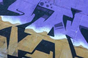 fragment de dessins de graffitis. le vieux mur décoré de taches de peinture dans le style de la culture de l'art de la rue. texture de fond colorée dans des tons violets photo