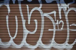 fragment d'un ancien dessin de graffitis colorés sur la porte de l'obturateur. image d'arrière-plan illustrant l'art de la rue, le vandalisme et la peinture murale avec de la peinture aérosol photo