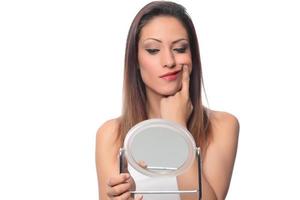 belle femme assise devant un miroir. visage d'une femme en bonne santé appliquant de la crème et du maquillage. publicité pour crème pour la peau, crème anti-rides, visage de bébé photo