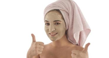 procédures de beauté concept de soins de la peau. jeune femme appliquant un masque d'argile de boue faciale sur son visage photo