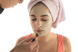 procédures de beauté concept de soins de la peau. jeune femme appliquant un masque d'argile de boue faciale sur son visage photo