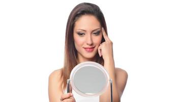 belle femme assise devant un miroir. visage d'une femme en bonne santé appliquant de la crème et du maquillage. publicité pour crème pour la peau, crème anti-rides, visage de bébé photo