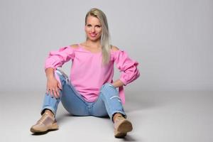 femme souriante à la mode blonde portant des accessoires modernes posant en studio photo