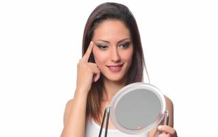 belle femme assise devant un miroir. visage d'une femme en bonne santé appliquant de la crème et du maquillage. publicité pour crème pour la peau, crème anti-rides, visage de bébé photo