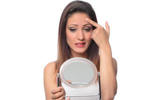 belle femme assise devant un miroir. visage d'une femme en bonne santé appliquant de la crème et du maquillage. publicité pour crème pour la peau, crème anti-rides, visage de bébé photo