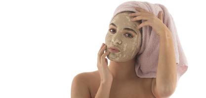 procédures de beauté concept de soins de la peau. jeune femme appliquant un masque d'argile de boue faciale sur son visage photo