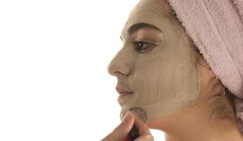 procédures de beauté concept de soins de la peau. jeune femme appliquant un masque d'argile de boue faciale sur son visage photo