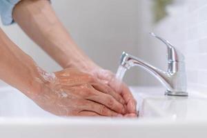 hommes se lavant les mains avec du savon et de l'eau propre devant le lavabo de la salle de bain pour éviter la propagation des germes. se laver les mains avec du savon. photo