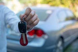 vente de voiture, vente de voiture, transaction, location de voiture pour les touristes étrangers concept le concessionnaire donne les clés de la voiture au nouveau propriétaire ou locataire avec un contrat d'assurance. photo