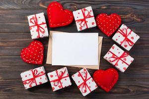 courrier enveloppe avec coeur rouge et boîte-cadeau sur fond de bois foncé. carte de saint valentin, concept de voeux d'amour ou de mariage photo