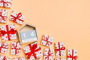 vue de dessus des coffrets cadeaux avec des coeurs rouges et un calendrier en bois sur fond coloré. le quatorze février. concept de la saint-valentin avec espace de copie photo