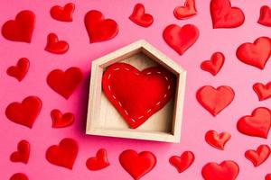 gros plan sur un coeur rouge dans une maison en bois décorée de petits coeurs sur fond coloré. La Saint-Valentin. concept de maison douce maison photo