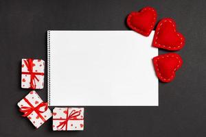 vue de dessus du cahier entouré de coffrets cadeaux et de coeurs sur fond coloré. notion de saint valentin photo