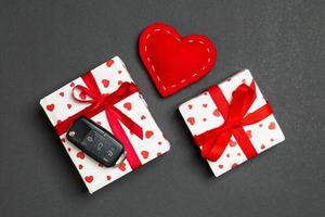 vue de dessus de la clé de voiture sur la boîte cadeau et les coeurs textiles rouges sur fond coloré. présent pour le concept de la saint valentin photo