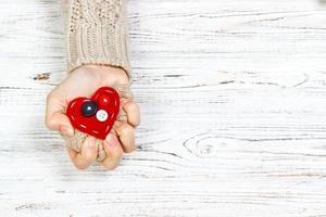 la main qui a serré le coeur rouge sur la table en bois. concept d'amour avec fond photo