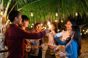 les jeunes fêtards asiatiques tiennent joyeusement des étincelles pour célébrer photo