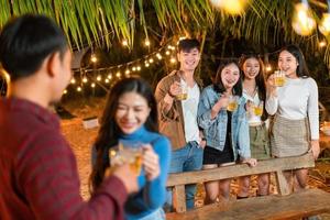 jeune couple partageant joyeusement une bière avec des amis lors d'une fête photo