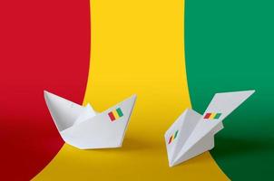 drapeau de la guinée représenté sur un avion et un bateau en papier origami. concept d'art fait à la main photo
