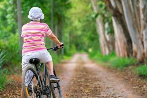 femme d'affaires senior, femme, balade à vélo ou vélo de montagne dans un parc de campagne près de la ville natale pour un exercice sain le week-end d'été photo