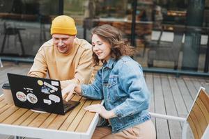 élégant jeune couple pigistes travaillant sur ordinateur portable dans le café de la rue photo