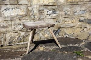 vieille petite chaise en bois dans la cour rurale près d'un mur de pierre. photo