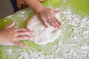 les mains pétrissent la pâte pâtisserie maison pour le pain ou la pizza fond de boulangerie - les mains de l'enfant préparent la pâte avec de la farine à bord photo