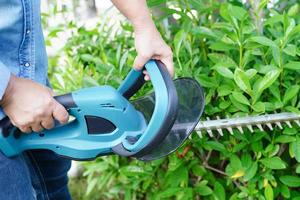 jardinier coupant le buisson par des taille-haies électriques dans le jardin. passe-temps à la maison. photo