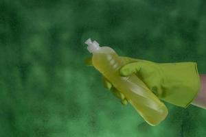 main avec gant de protection tenant l'emballage des produits de nettoyage utilisés pour l'hygiène domestique