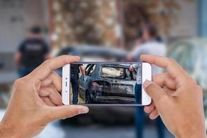 accident de voiture endommagé avec la main à l'aide d'un smartphone prenant une photo