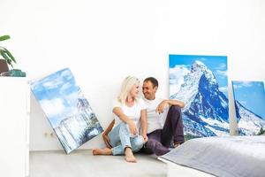 jeune couple accroche une grande toile photo à la maison