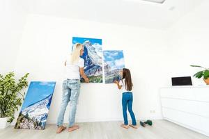 mère et fille accrochent une grande toile photo à la maison