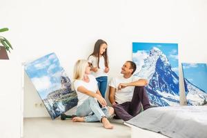 dans un nouvel appartement, la famille accroche une grande toile photo sur un mur blanc vide à la maison