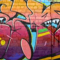 fragment coloré abstrait de peintures graffiti sur le vieux mur de briques. composition d'art de rue avec des parties de lettres non écrites et des taches multicolores. texture de fond sous-culturelle photo