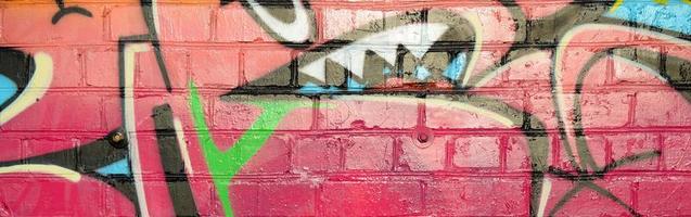 fragment coloré abstrait de peintures graffiti sur le vieux mur de briques. composition street-art avec des parties de lettres sauvages et des taches multicolores. texture de fond sous-culturelle photo