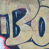 fragment de dessins de graffitis. le vieux mur décoré de taches de peinture dans le style de la culture de l'art de la rue. texture de fond colorée dans des tons chauds photo