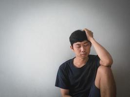 tristesse homme asiatique assis au mur photo