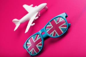 lunettes de soleil turquoise avec drapeau du royaume-uni dans les lentilles sur fond rose fou avec avion blanc. t photo