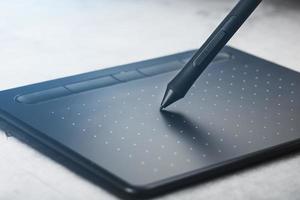 stylo avec une tablette graphique entre les mains du designer, gros plan. gadget pour l'art et le travail. photo