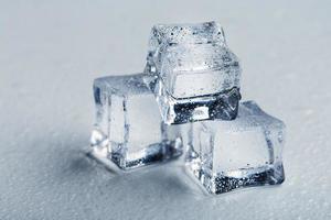 glaçons sous forme de pyramide avec gouttes d'eau en gros plan en macro sur fond blanc. photo