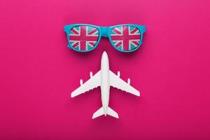 lunettes de soleil turquoise avec drapeau du royaume-uni dans les lentilles sur fond rose fou avec avion blanc. t photo