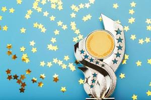 coupe du trophée d'or avec des étoiles célébrant le succès sur fond bleu. photo