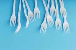 fourchettes en plastique blanc de vaisselle jetable sur fond bleu. photo