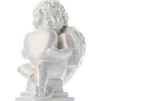 statue de chérubin isolé sur fond blanc. l'ange tient le coeur. l'amour photo