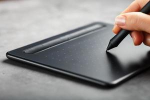 tablette graphique avec un stylo entre les mains du concepteur, gros plan. gadget pour la créativité et le travail photo