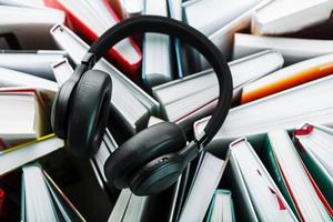 des écouteurs noirs sans fil se trouvent sur les livres. le concept d'apprentissage à travers un livre audio. pour écouter le livre. photo