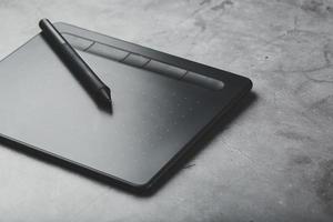 tablette graphique avec un stylo sur fond gris, le travail d'un designer, artiste et photographe. la vue du haut photo