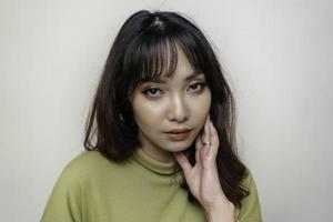 un visage joyeux de beauté de jeune mannequin asiatique portant un haut vert. soin du visage beauté soins de la peau, spa, concept de santé féminine. photo